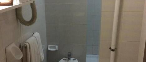 Um banheiro pequeno com pia, bidê e vaso sanitário.