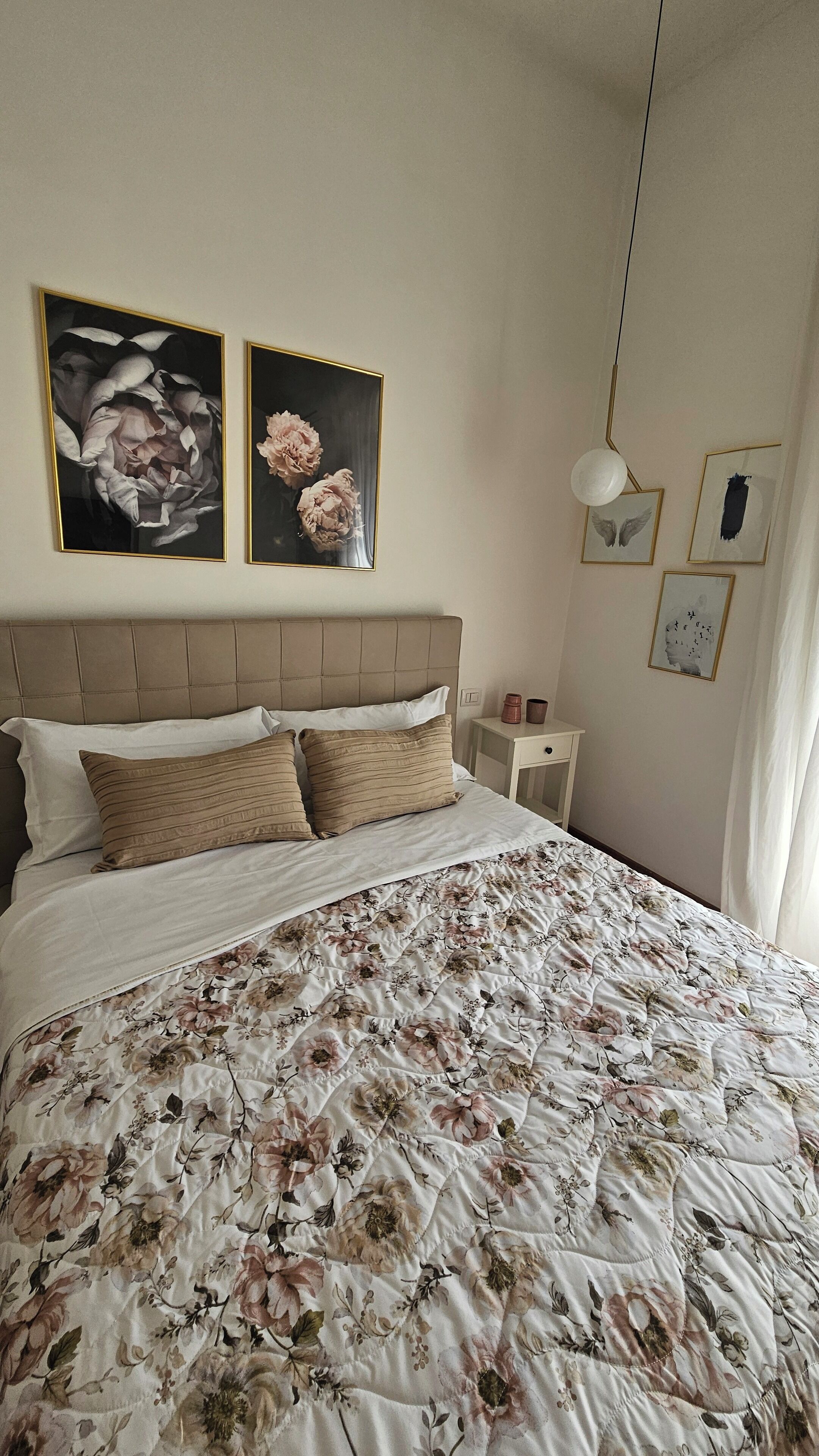 Un dormitorio con una cama grande, cabecera, mesita de noche y decoración en la pared.