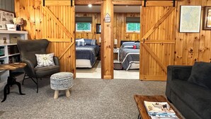 Une chambre confortable, aménagée dans le style d’un chalet, avec un lit, un fauteuil, une table basse et une bibliothèque.