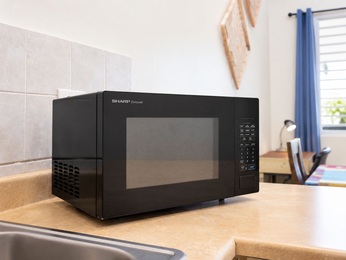 A black Sharp Carousel microwave on a kitchen counter.