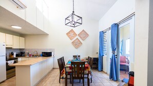 Uma cozinha moderna com uma ilha central, uma área de refeições com cadeiras e vista para o exterior.