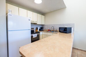 A kitchen with a refrigerator, stove, microwave, and sink. - Golden Dream Villas 306 A (Isabela)