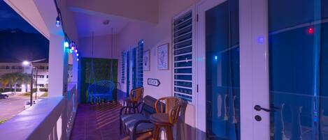 A balcony with wicker chairs, a sign indicating 'BEACH', and a view of the street at night.