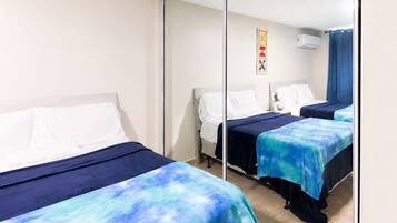A hotel room with two beds, a large mirror, and a ceiling fan.