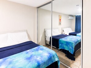 A hotel room with two beds, a large mirror, and a ceiling fan. - Golden Dream Villas 306 A (Isabela)