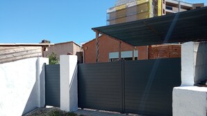 Un área cercada con un muro de concreto y una reja de metal.