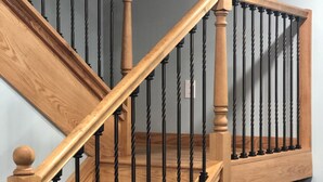 A wooden staircase with black balusters and a wooden handrail.