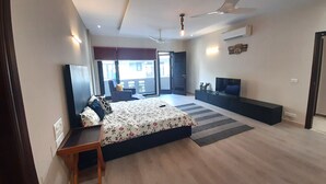 Un dormitorio moderno con cama, escritorio, televisión y ventilador de techo.