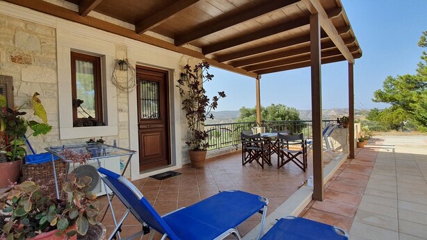 A covered outdoor area with a stone wall, wooden door, and potted plants. - Aelia Villa & Apartments with enchanting views of the Messara plain (Kamilari)