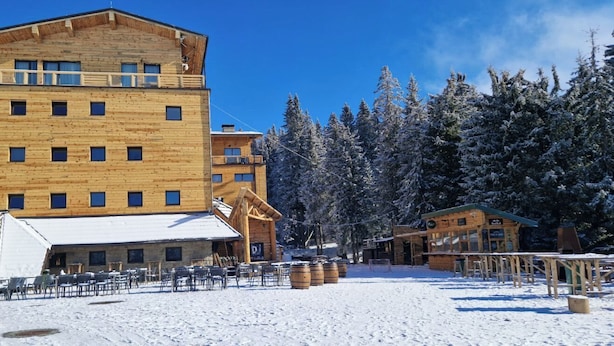 A wooden lodge with multiple floors and a snow-covered landscape.