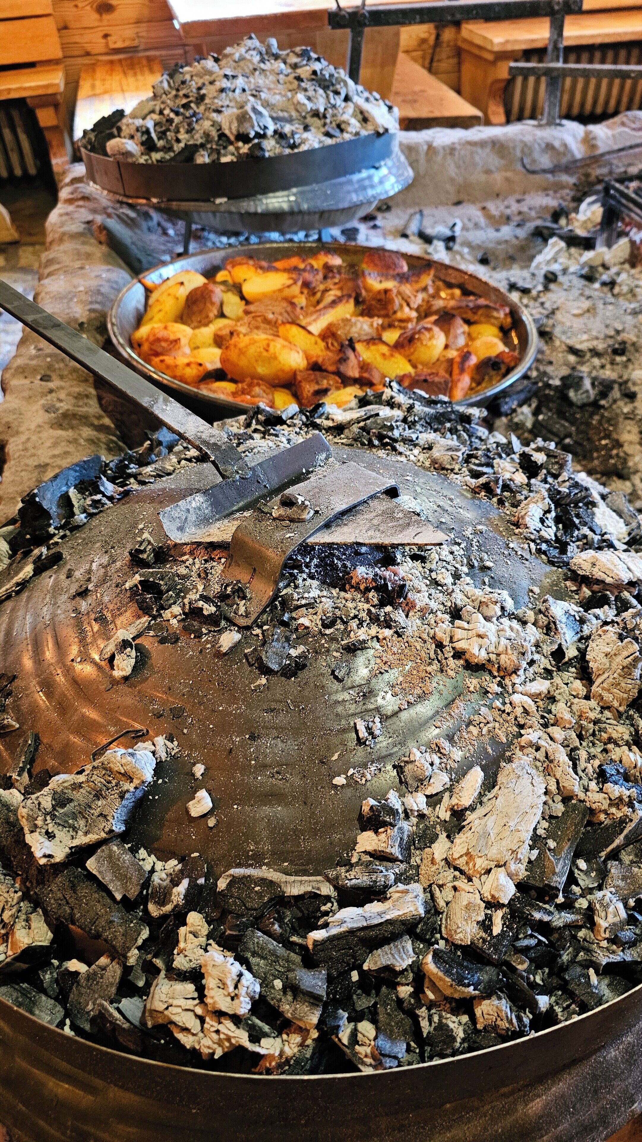 Ein großer Metalltopf, gefüllt mit Holzkohle und Asche, mit einem Metallspatel darauf.