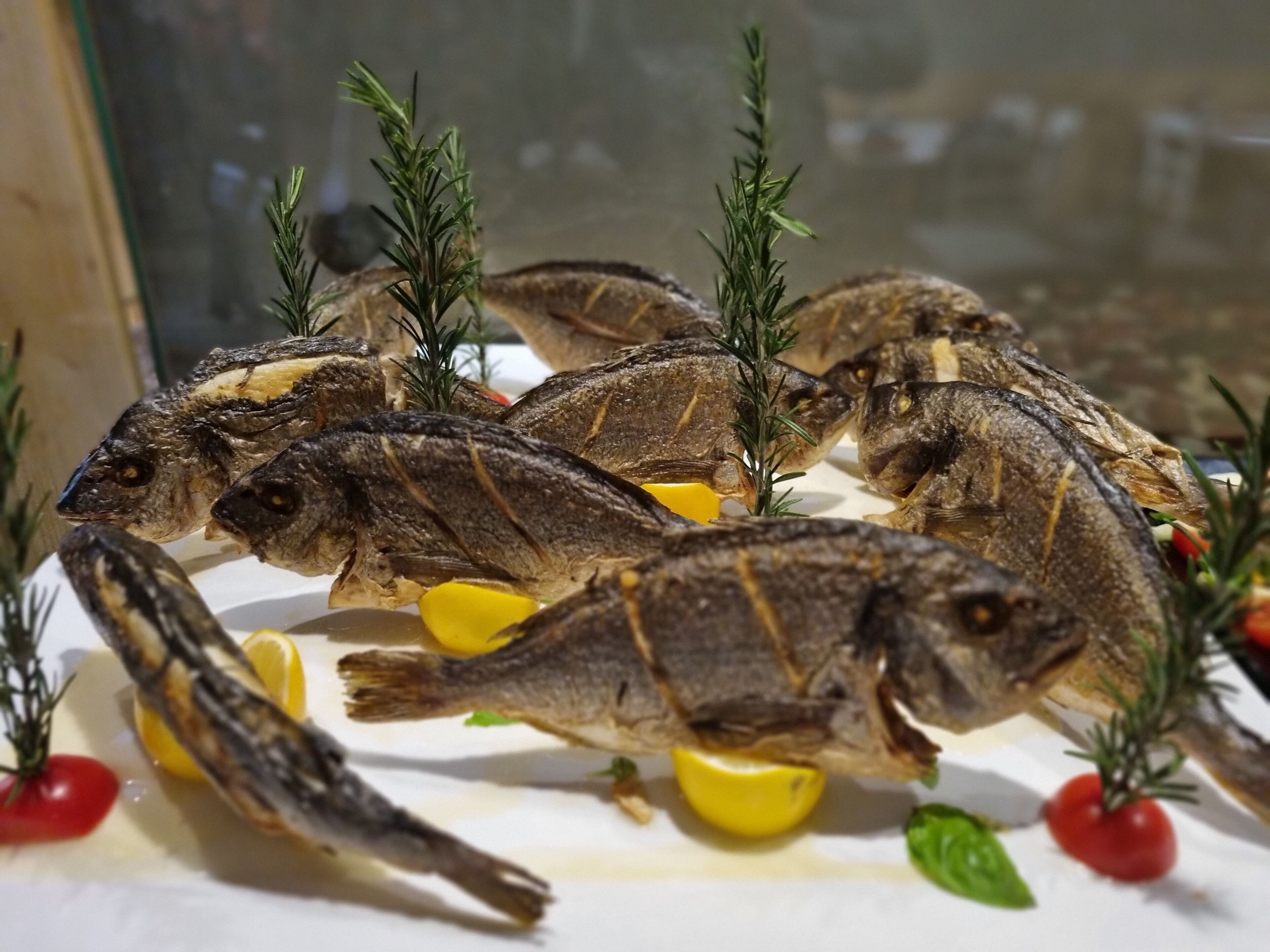 En borddækning med flere hele fisk, citronskiver og rosmarin.