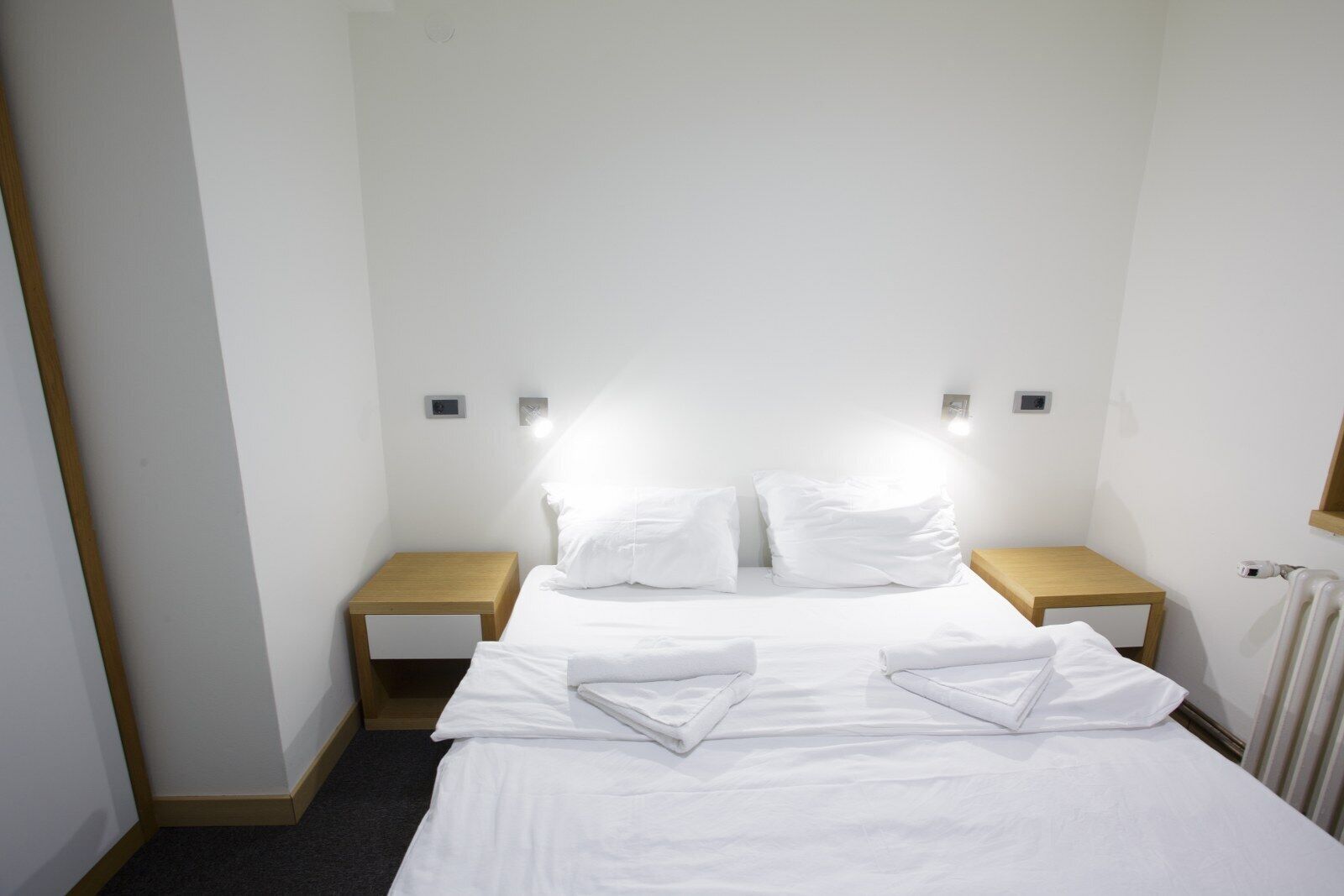 Ein Hotelzimmer mit einem Bett, zwei Nachttischen und Wandleuchten.
