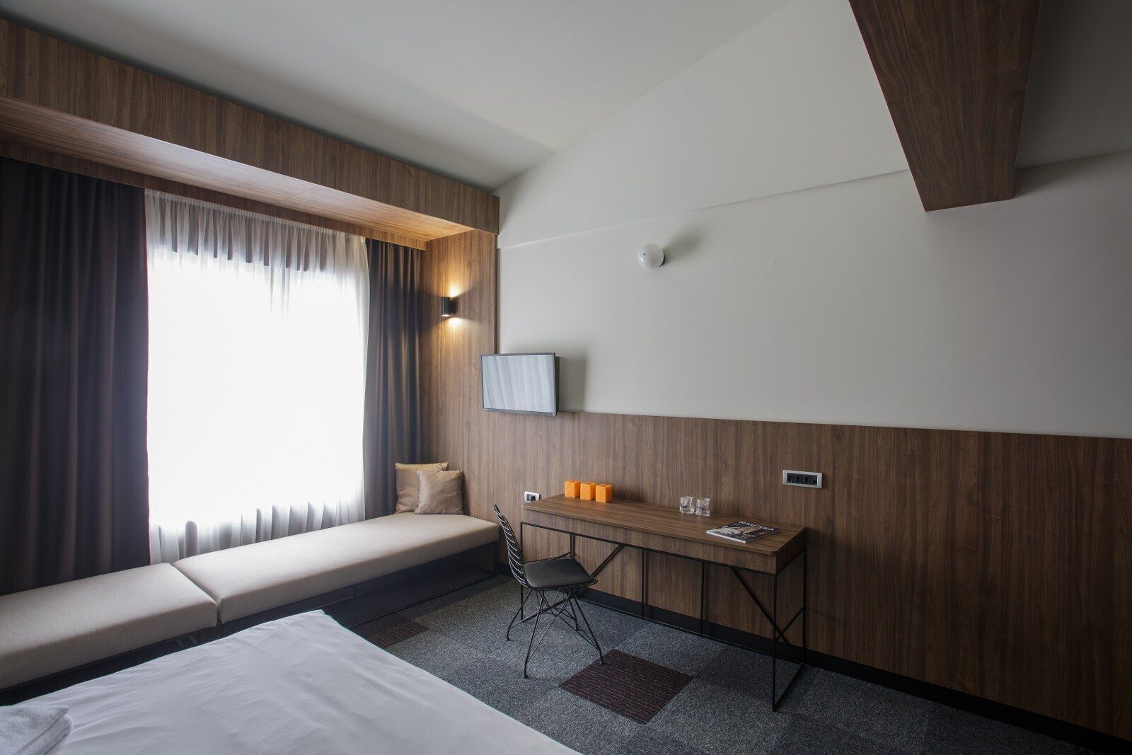 Et moderne hotelværelse med seng, skrivebord og siddeområde.