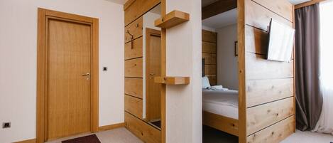 A room with a wooden wardrobe, a bed, and a TV mounted on the wall.
