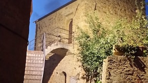 A narrow stone pathway leading to a building with a stone facade and an arched entrance. - Casa il Ciliegio (Terzorio)