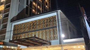 Un hôtel à plusieurs étages doté d’une façade moderne, de grandes fenêtres et d’un espace d’entrée couvert avec des sièges.