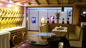 L’intérieur de ce restaurant chaleureux est agrémenté de poutres en bois, d’une longue table en bois et d’un espace détente avec des fauteuils confortables.