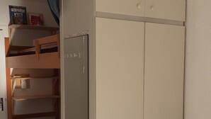 A compact room with a bunk bed, a wardrobe, and a small table. - Studio Chaleureux en Montagne (Puyvalador)