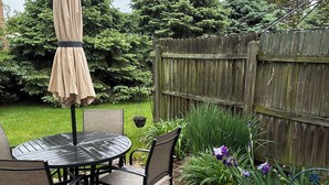 Une terrasse extérieure avec une table ronde et des chaises, un parasol et une clôture en bois.
