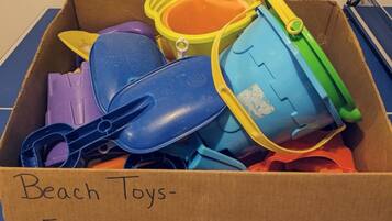A cardboard box labeled "Beach Toys" with a note instructing to wash and return the toys.