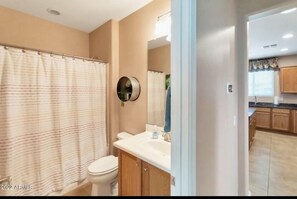 A bathroom with a shower curtain, toilet, sink, and mirror. - All the amenities of Sun City resort living at Merrill Ranch in Florence, AZ.  (Florence)