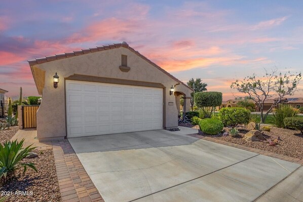 A single-story house with a garage, a landscaped front yard, and a clear sky. - All the amenities of Sun City resort living at Merrill Ranch in Florence, AZ.  (Florence)