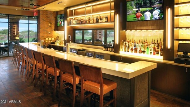 Un espace bar doté d’un long comptoir, de plusieurs options de sièges et d’un écran de télévision diffusant des images de golf.