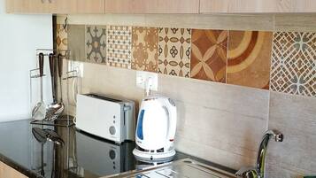 A kitchen with wooden cabinets, a black countertop, a toaster, a kettle, and a sink.