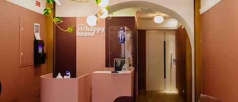 A reception area with a modern design, including a reception desk, a digital information kiosk, and a clear glass chair.