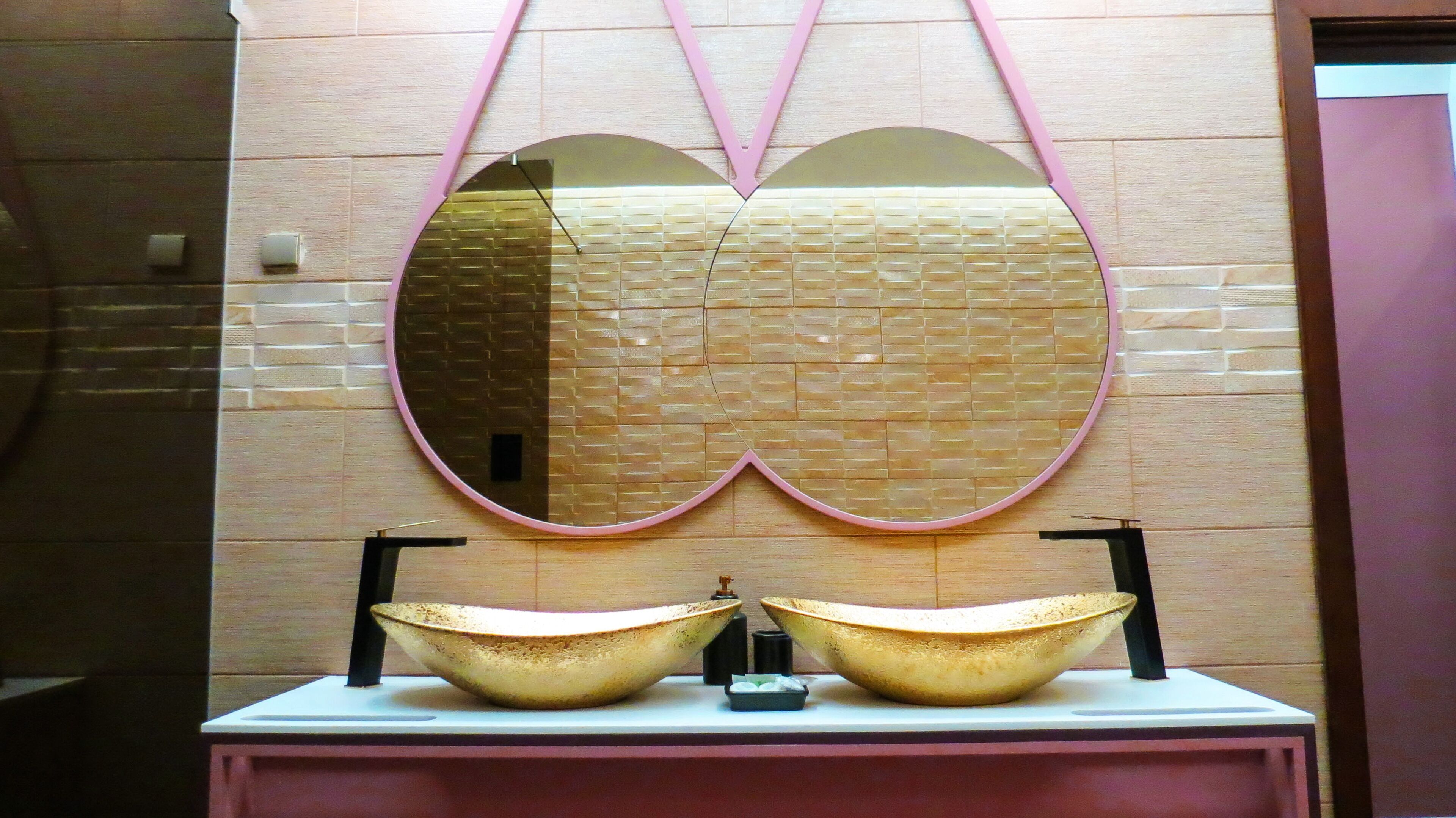 A bathroom vanity with a double basin sink and a large mirror with a pink frame.