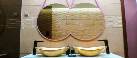 A bathroom vanity with a double basin sink and a large mirror with a pink frame.