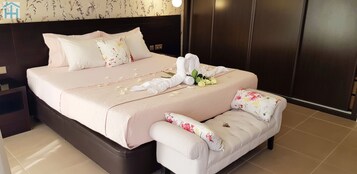 Una cama bien hecha con almohadillas florales, una mesita de noche y un pequeño sofá con cojines estampados.