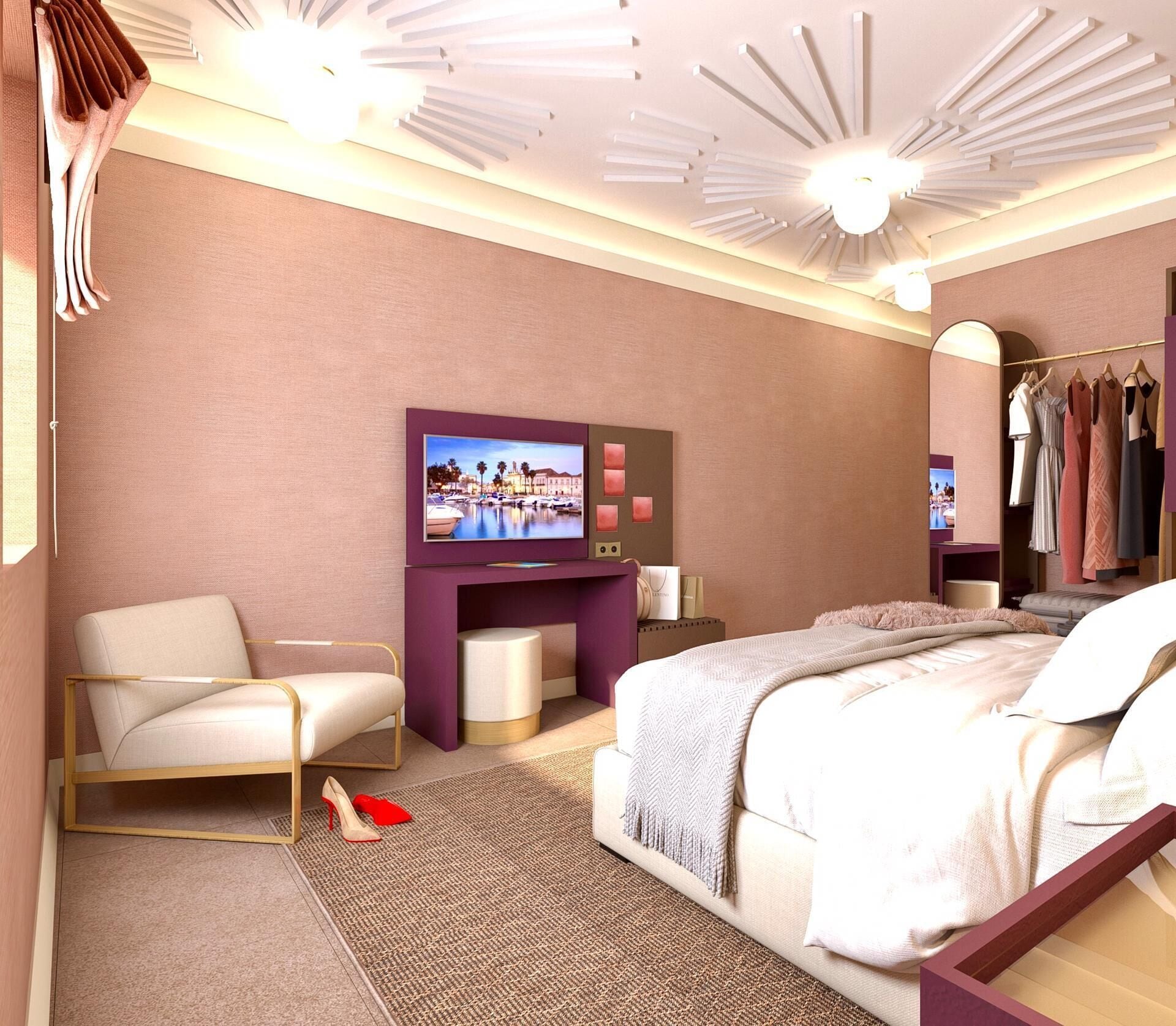 A modern hotel room with a bed, a seating area with a chair, a TV mounted on the wall, and a wardrobe with clothes.