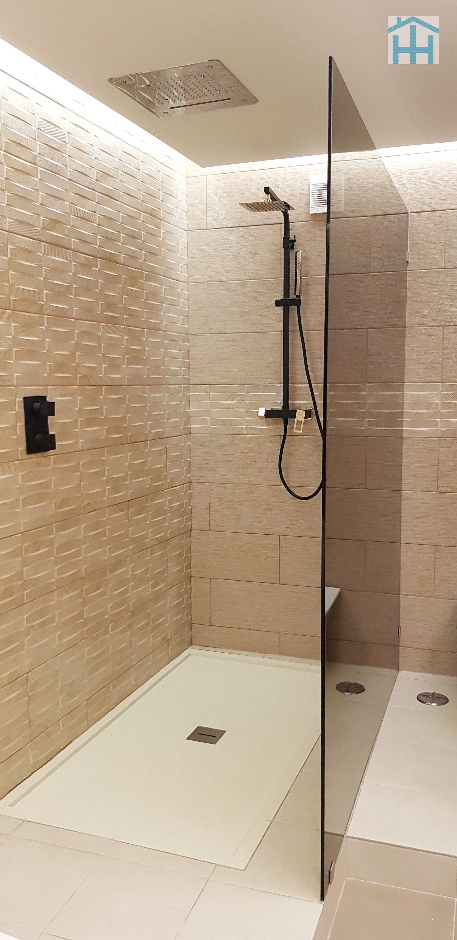 A modern bathroom with a glass shower enclosure, a tiled wall, and a visible showerhead.