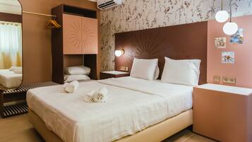 A hotel room with a large bed, a bedside table, a mirror, and a wall-mounted air conditioner.