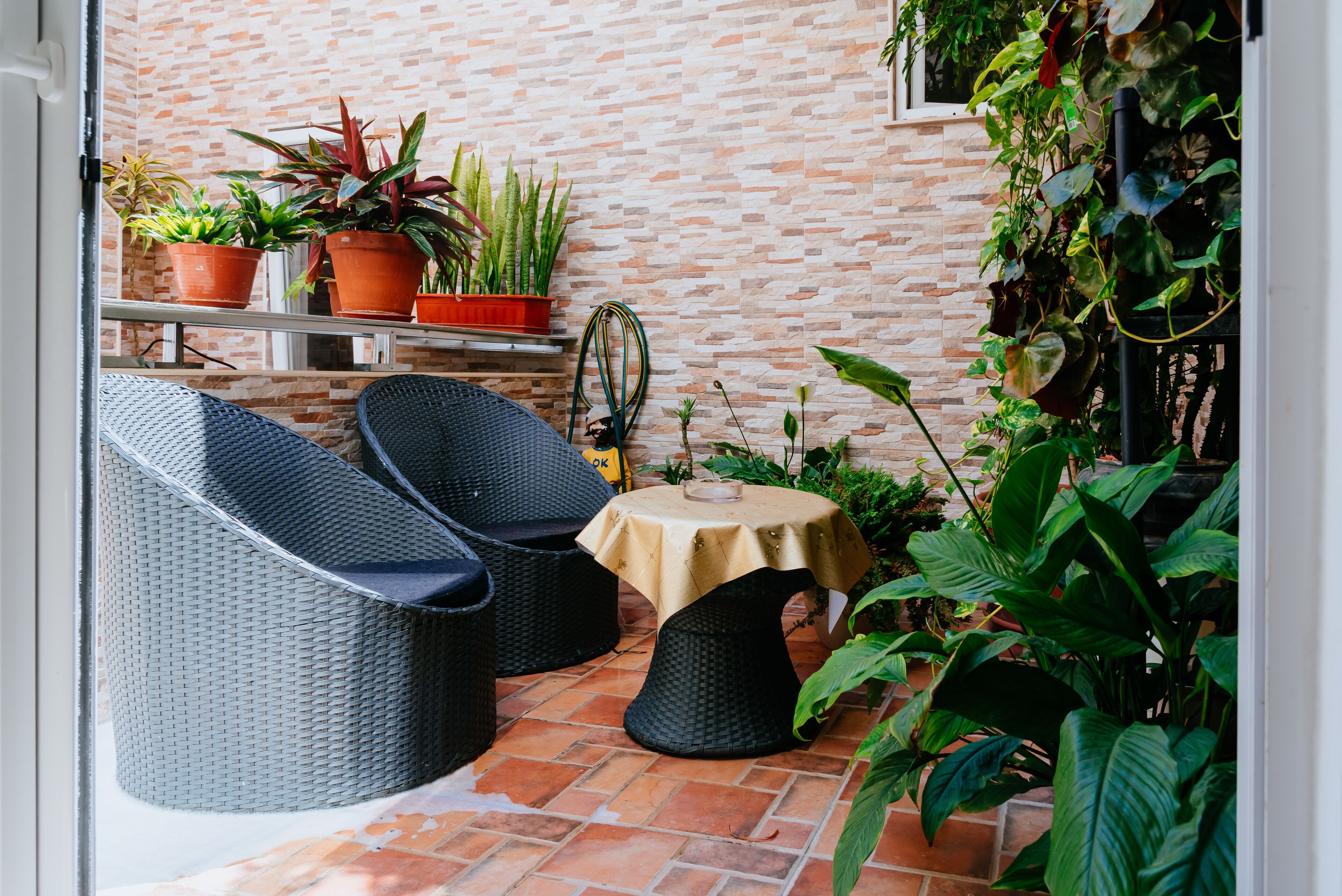 A patio area with wicker furniture, a small table, and potted plants.