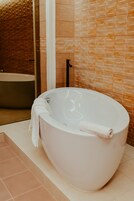 Um banheiro moderno com banheira independente, box de vidro e piso revestido de azulejos.