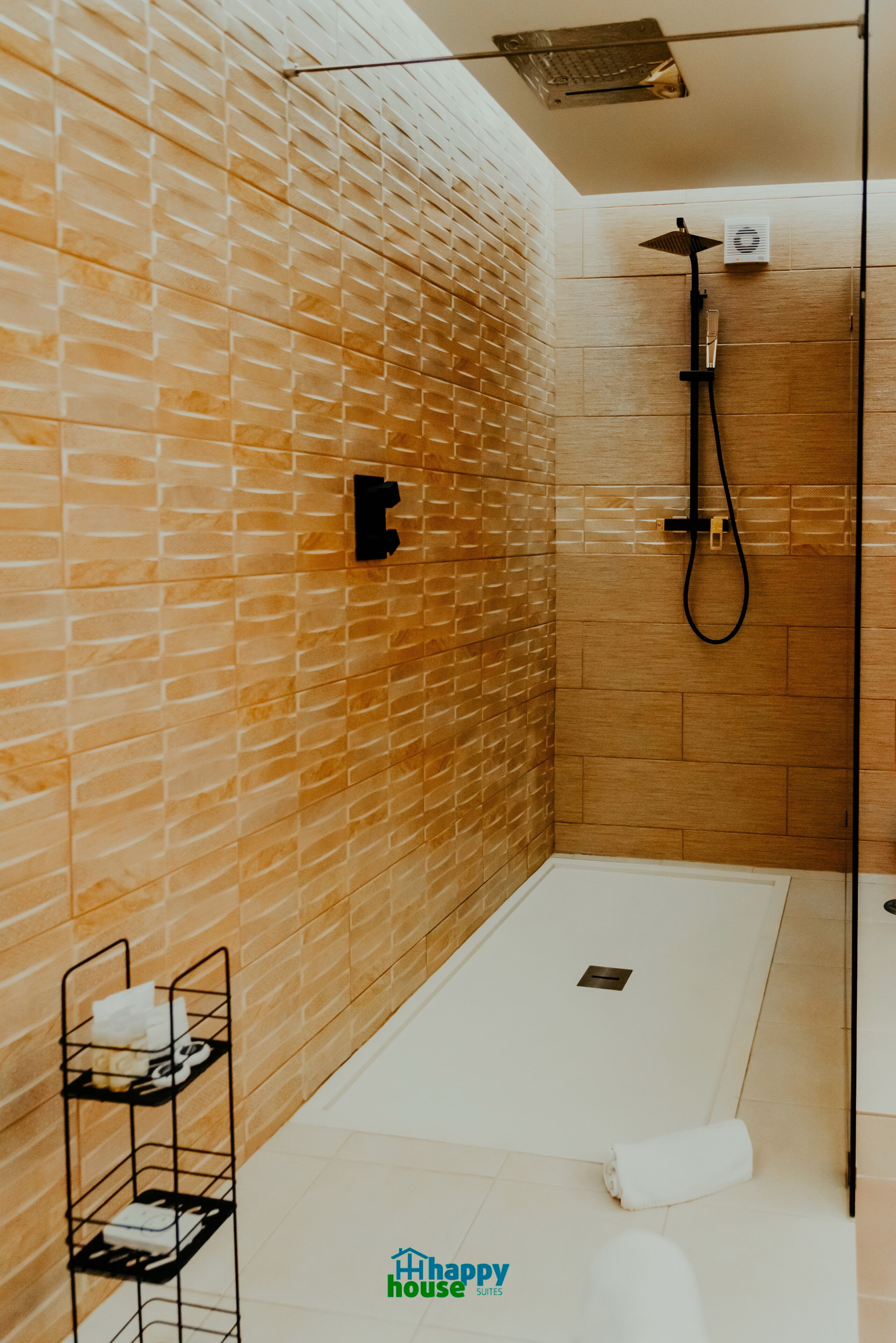 Un baño moderno con pared de ladrillo, zona de ducha y un pequeño estante con toallas.