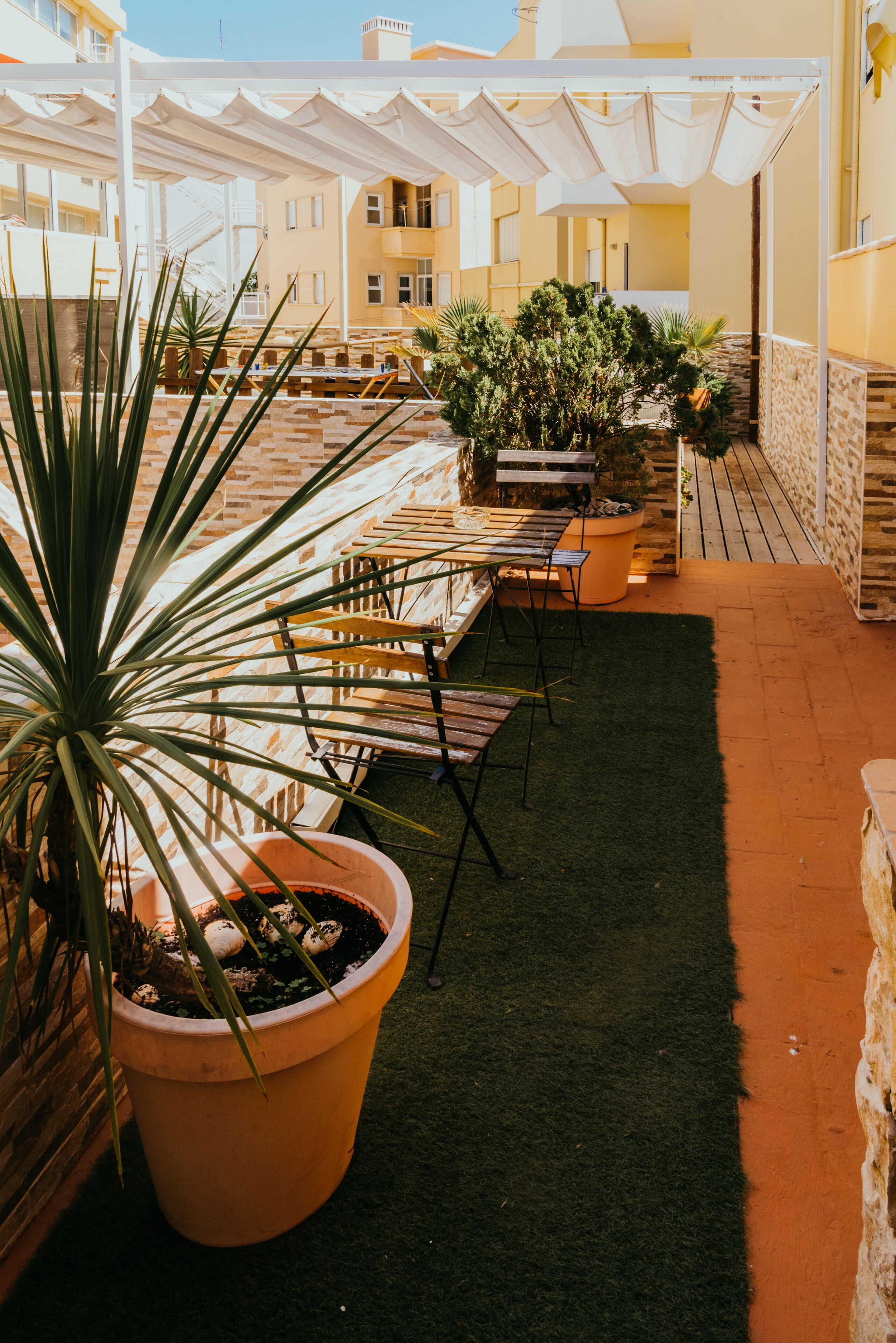 Una terrazza sul tetto con area salotto, piante in vaso e vista sull'interno dell'edificio.