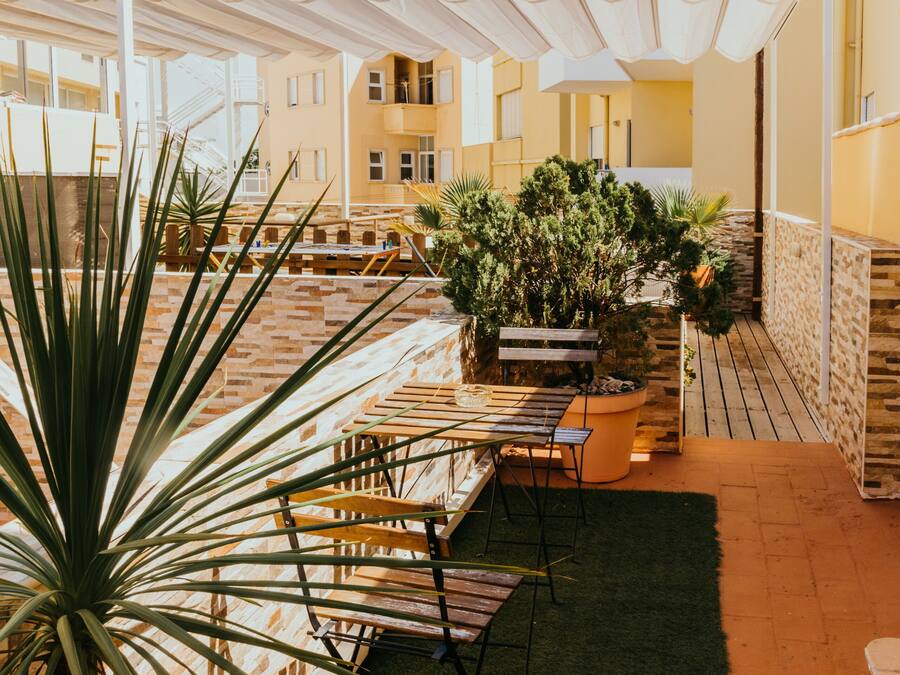 En tagterrasse med siddeplads, plantekasser og udsigt til bygningens indre.