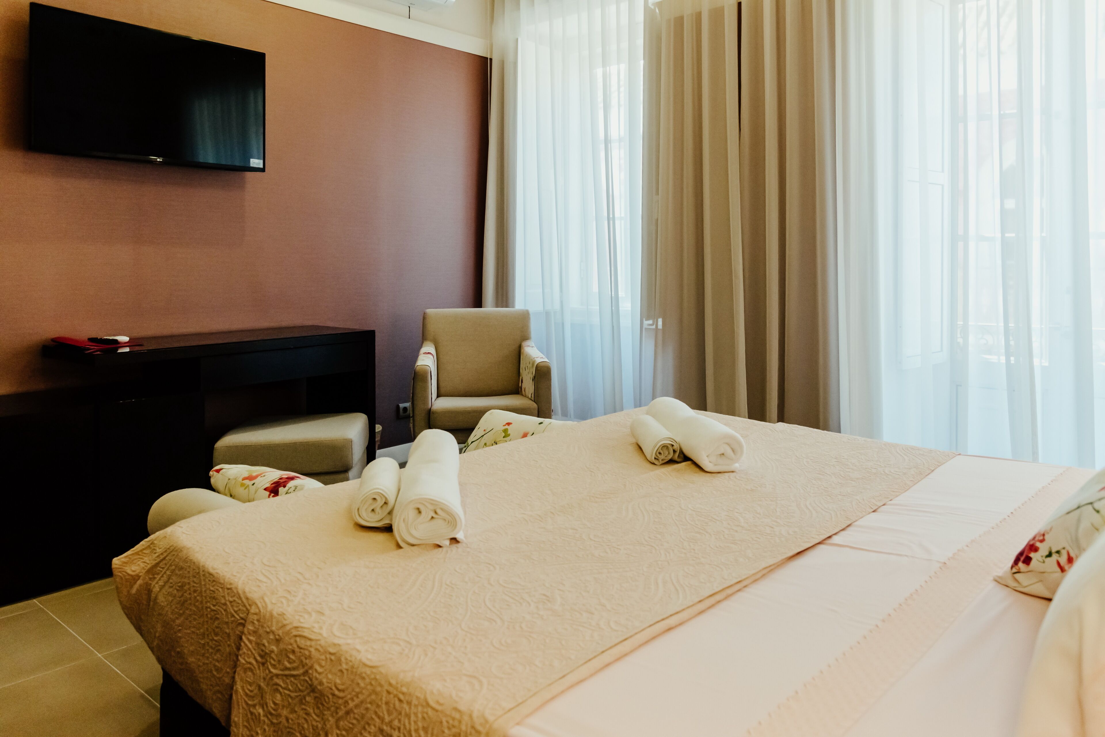 A hotel room with a bed, a chair, a desk, and a TV.