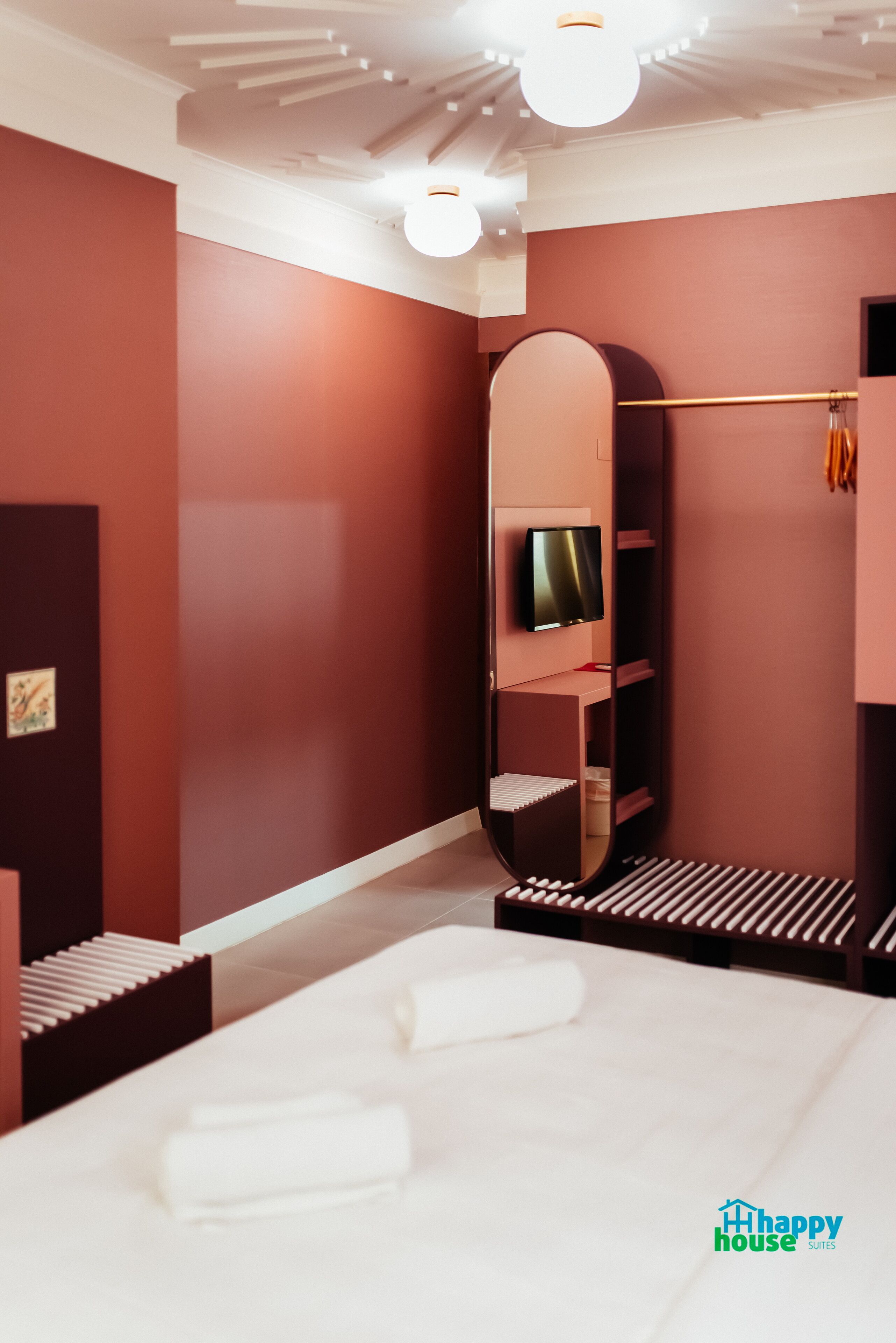 A modern bedroom with a large bed, a round mirror, a TV, and a wardrobe.