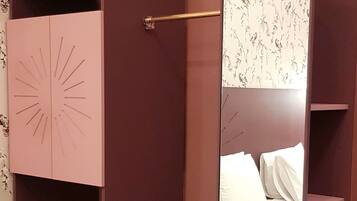 Un armario con espejo, repisas integradas y una cama con ropa blanca.