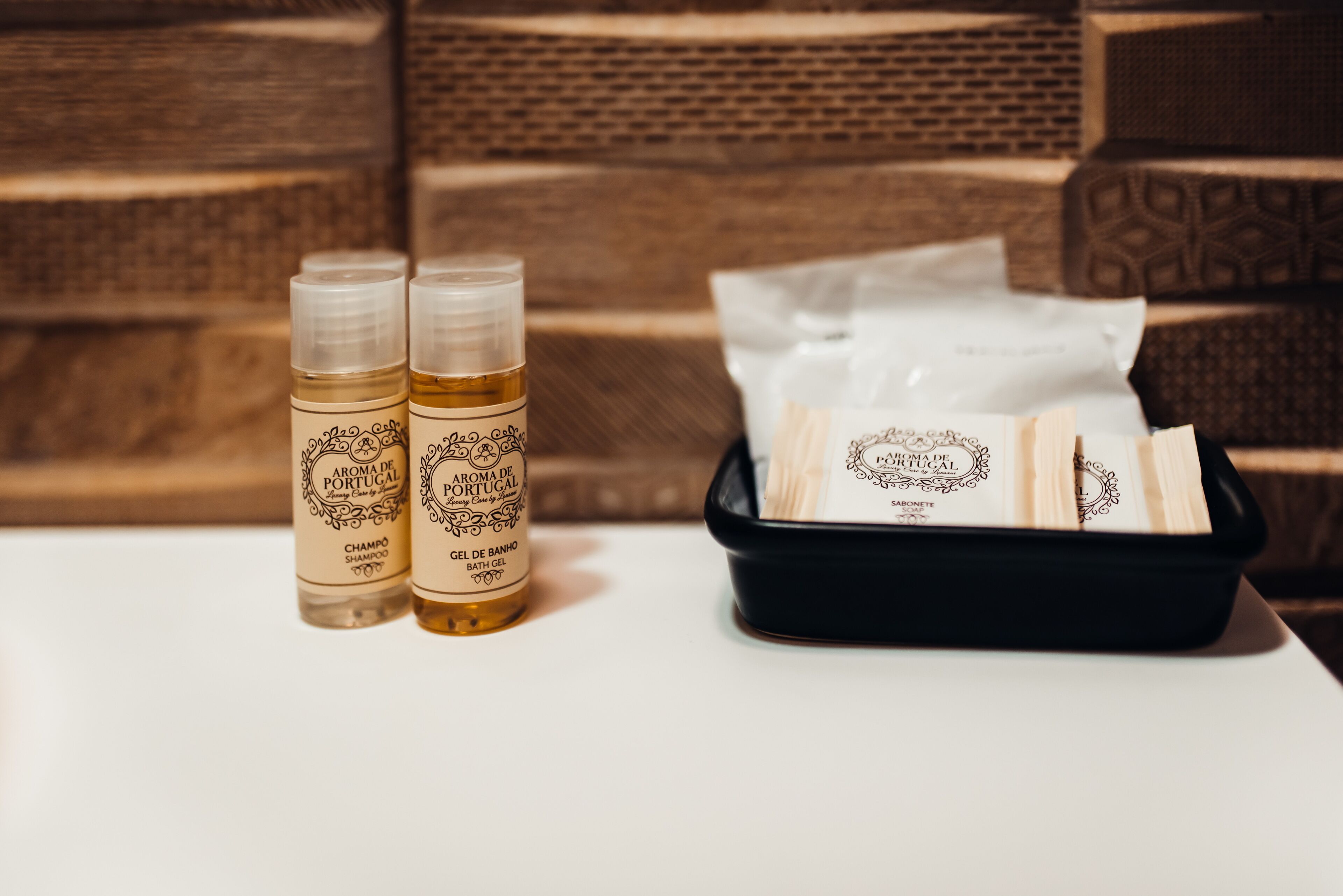 Duas garrafas de shampoo e gel de banho, e um tabuleiro preto com toalhas brancas.