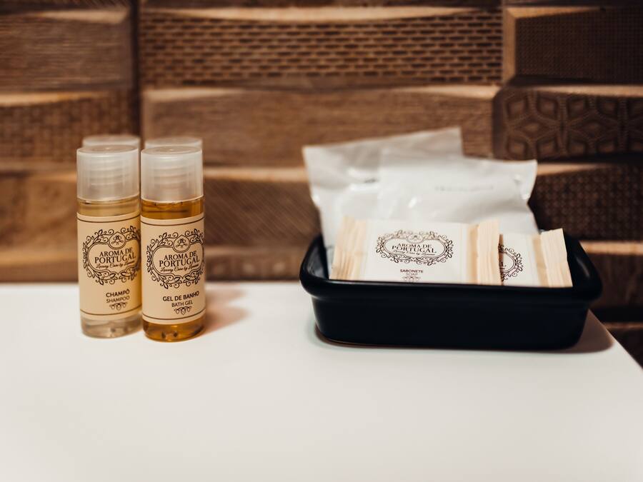 Duas garrafas de shampoo e gel de banho, e um tabuleiro preto com toalhas brancas.