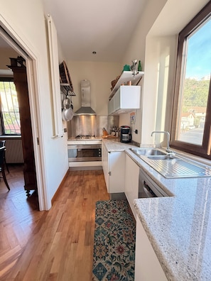 A compact kitchen with a gas stove, oven, microwave, and a sink.