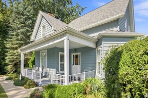 Ein zweistöckiges Haus mit überdachter Veranda, Eingangstür und Schornstein.