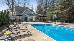 A swimming pool with lounge chairs and a basketball hoop in a backyard setting. - (2027 OPEN!) New Buffalo Home With Private Pool and Hot Tub! (New Buffalo)