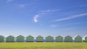 A row of green-roofed structures with a clear blue sky in the background. - The Escape (Brighton)